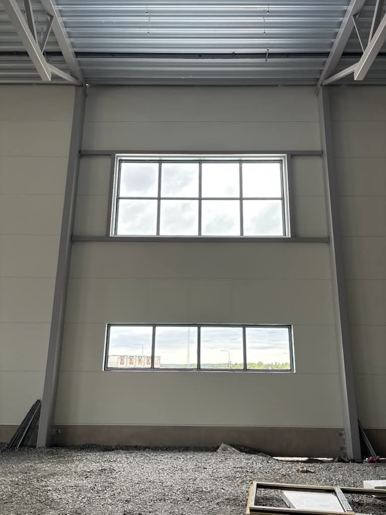 Nya fönster högt upp i en industrihall, sett inifrån