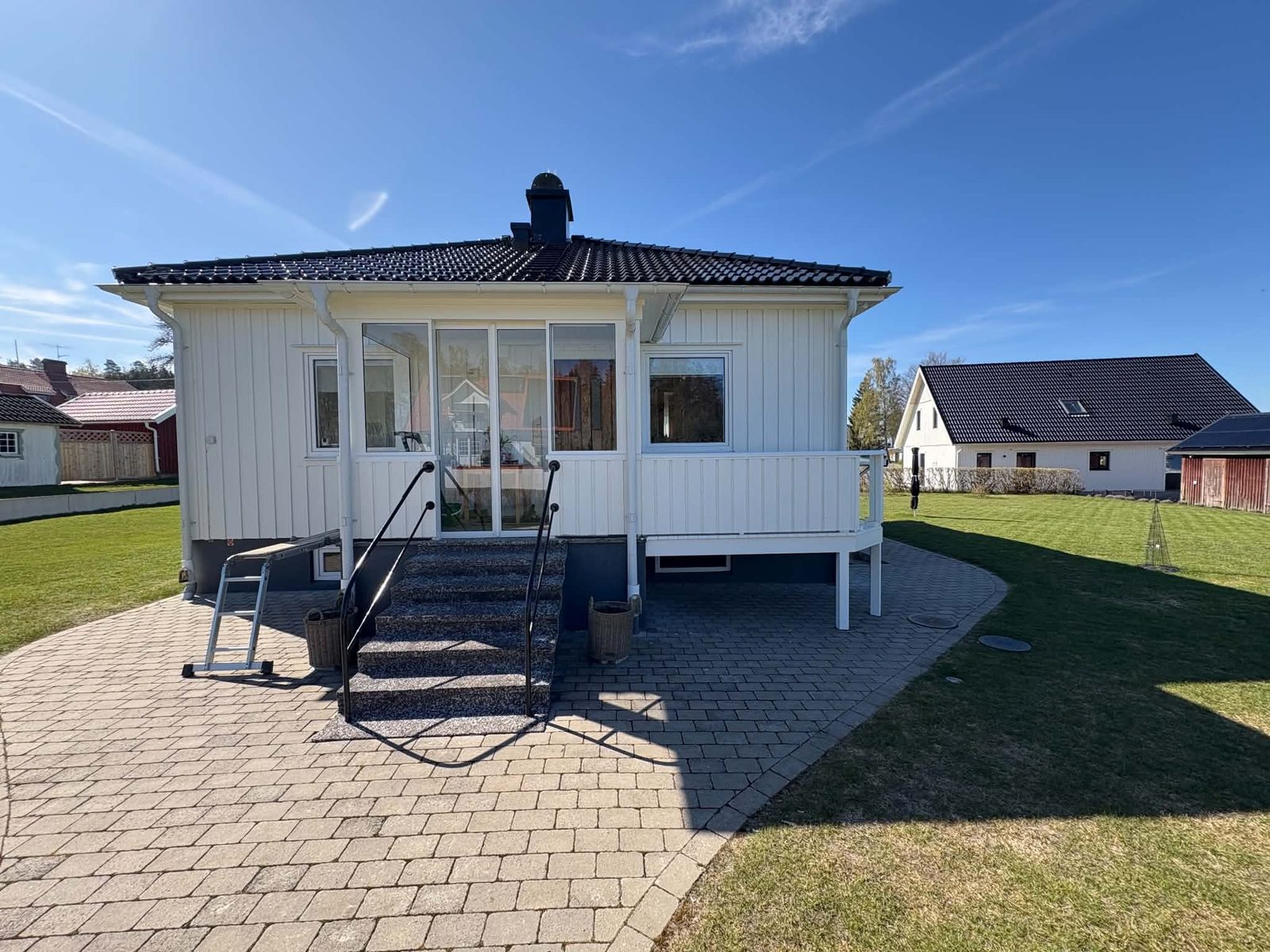 Inglasad farstu med trappa på en vit villa i Otterbäcken