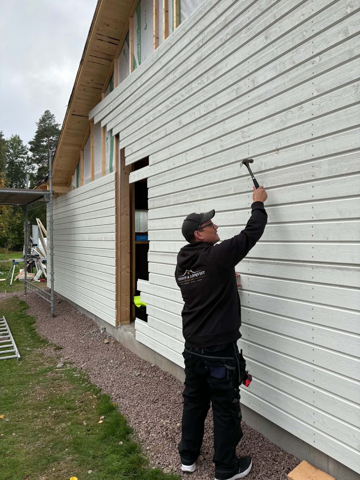 Hantverkare spikar ny vit fasadpanel