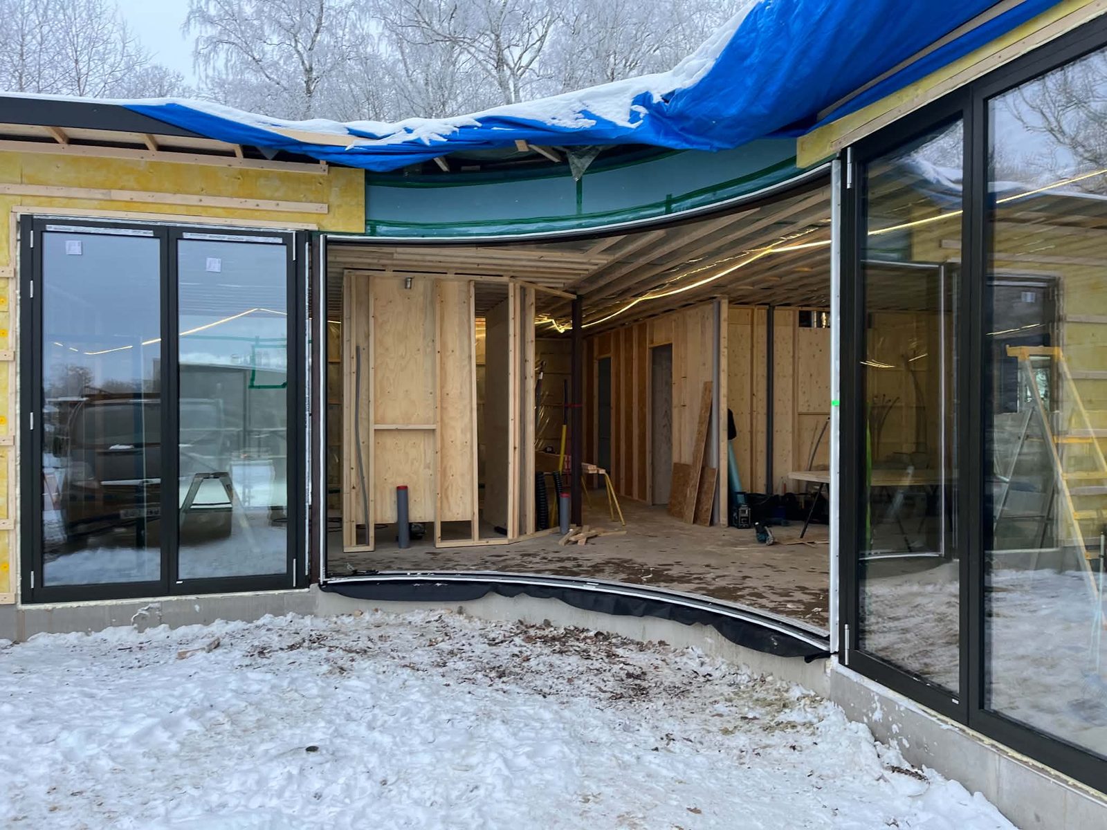 Utbyggnad med stora glaspartier i Hjo under bygget, med snö på marken